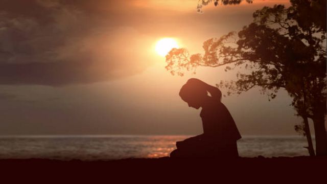 Silhouette of woman read the bible on the beach with a sunset sky background